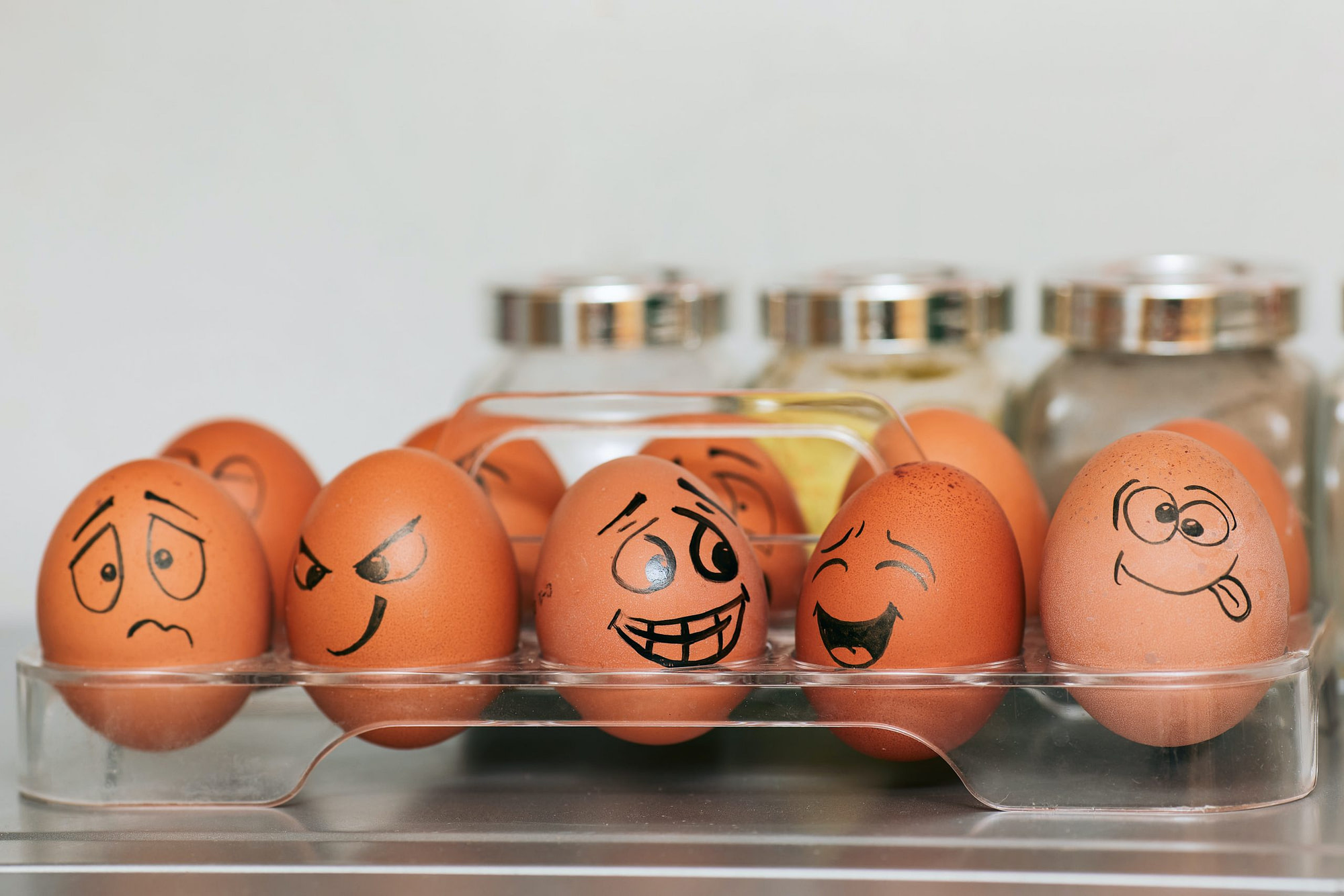 Eggs in a carton with faces drawn on the in black ink
