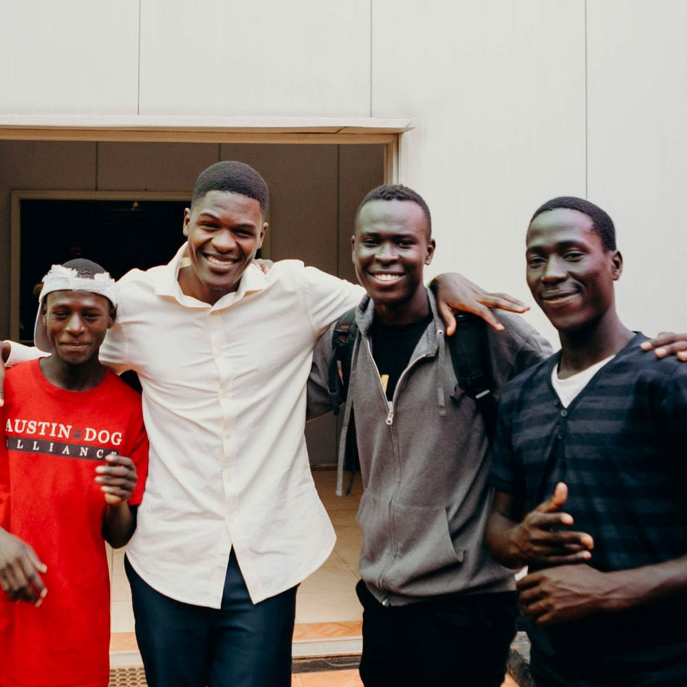 Four men smiling at the camera with their arms on each others' shoulders