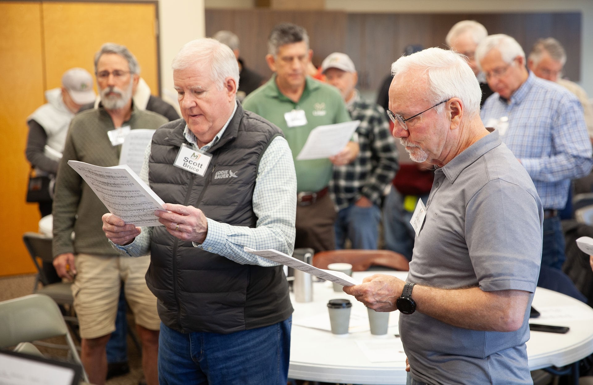 Men singing from sheet music at rehearsal
