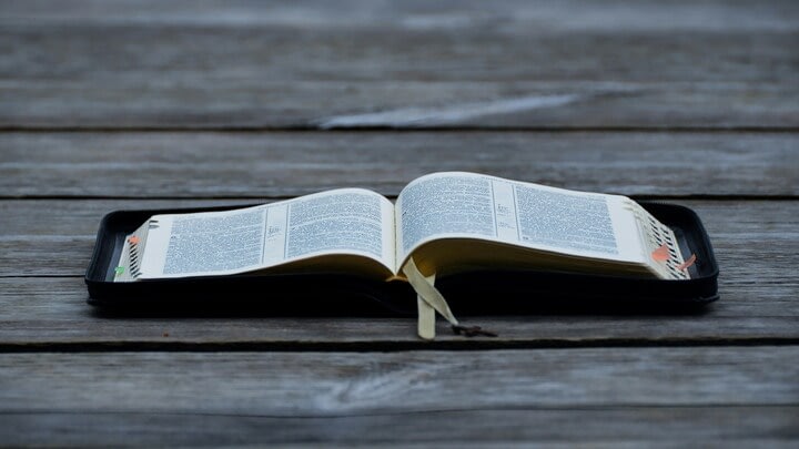 Open book on rustic wooden table outdoors