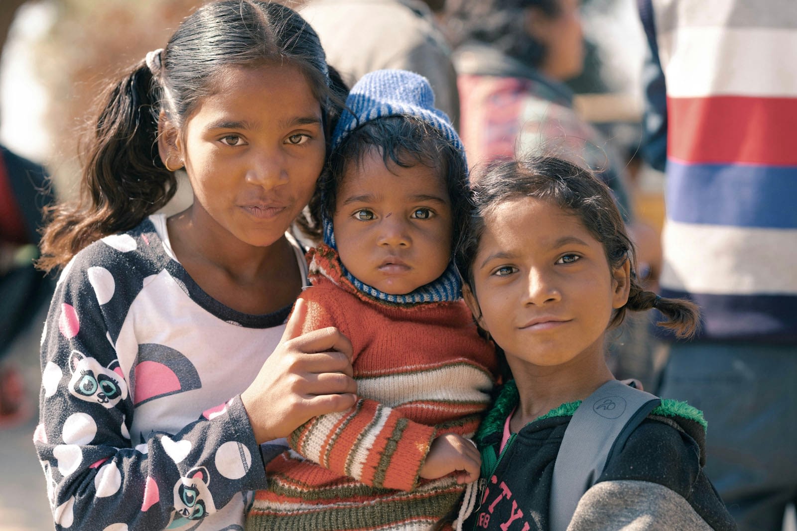 Three children posing together outdoors.