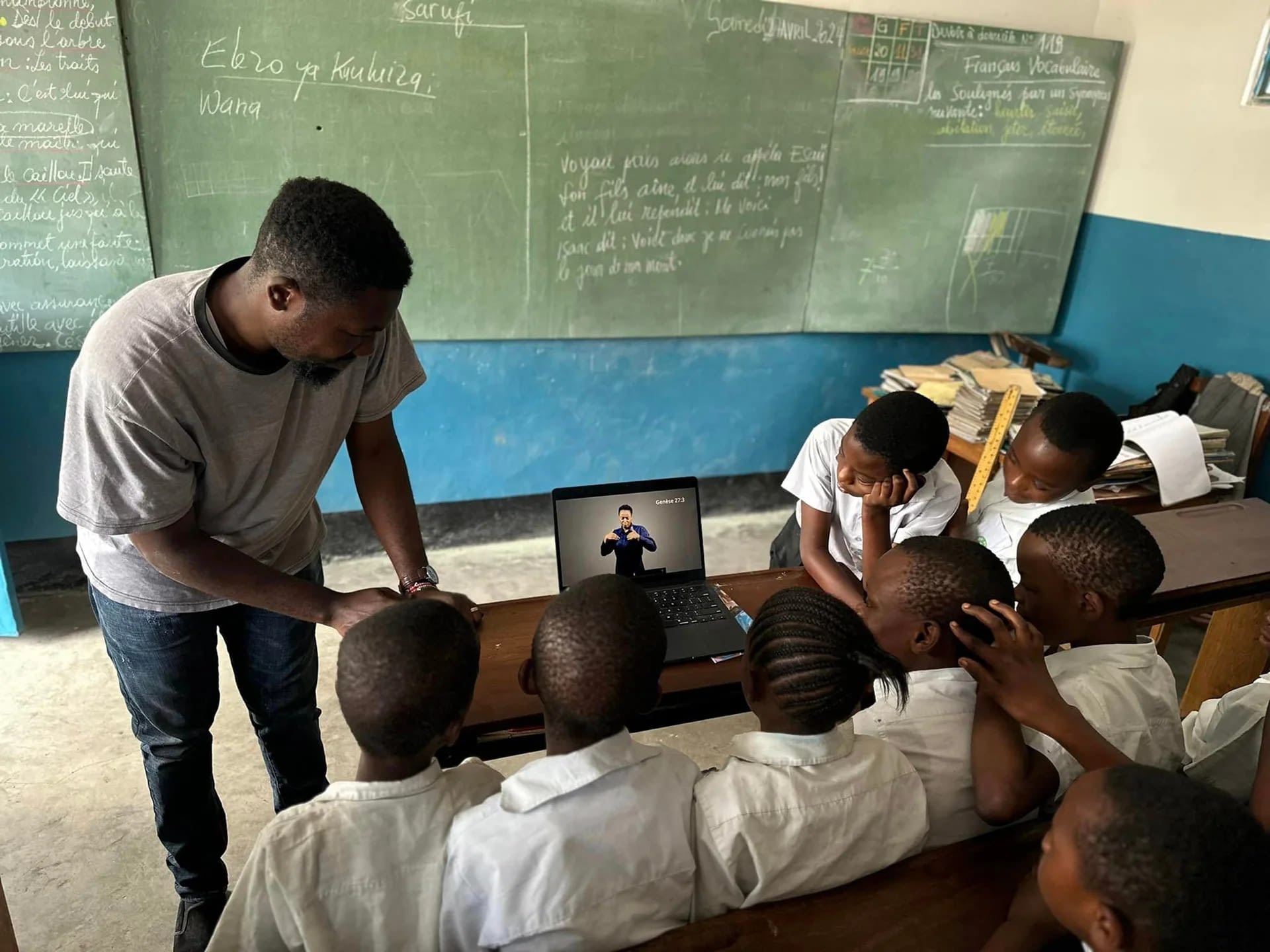 Teacher and students in classroom using a laptop.