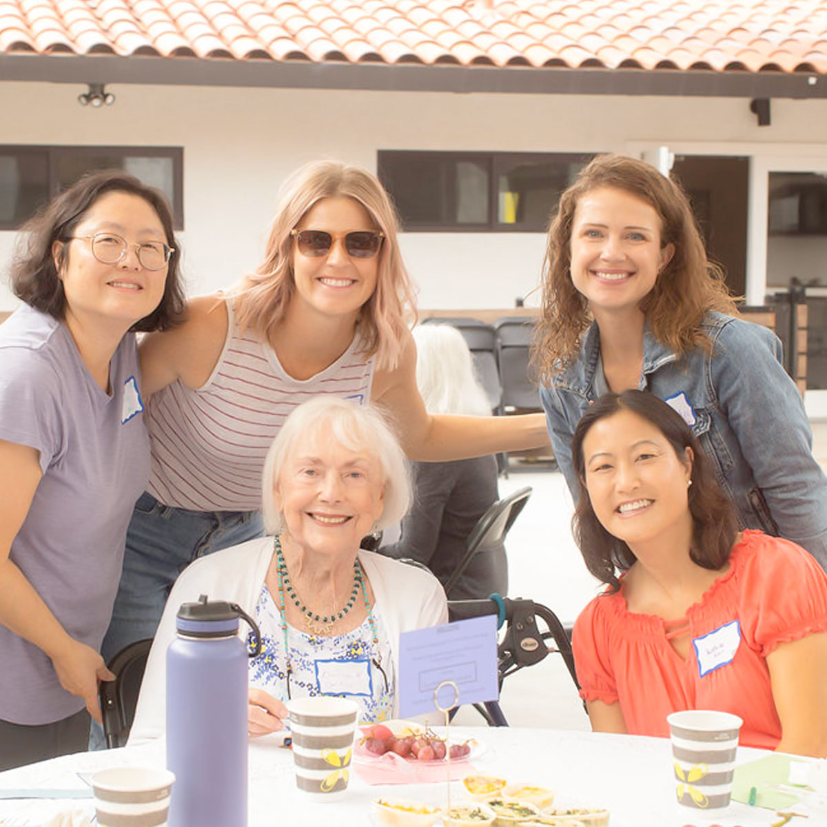 Women of varied ages posing for photo at a table outdoors