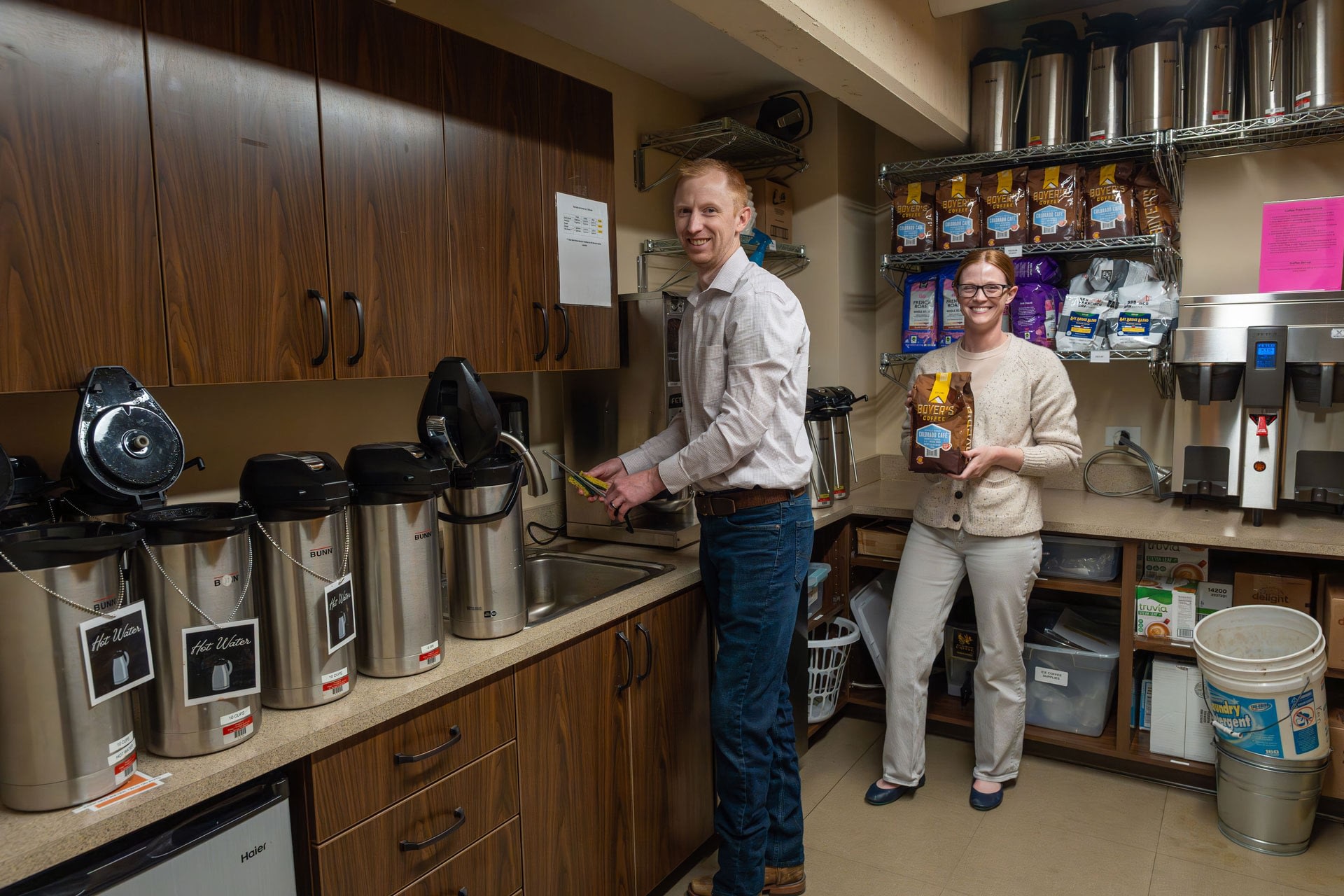 Two coworkers in office coffee supply room