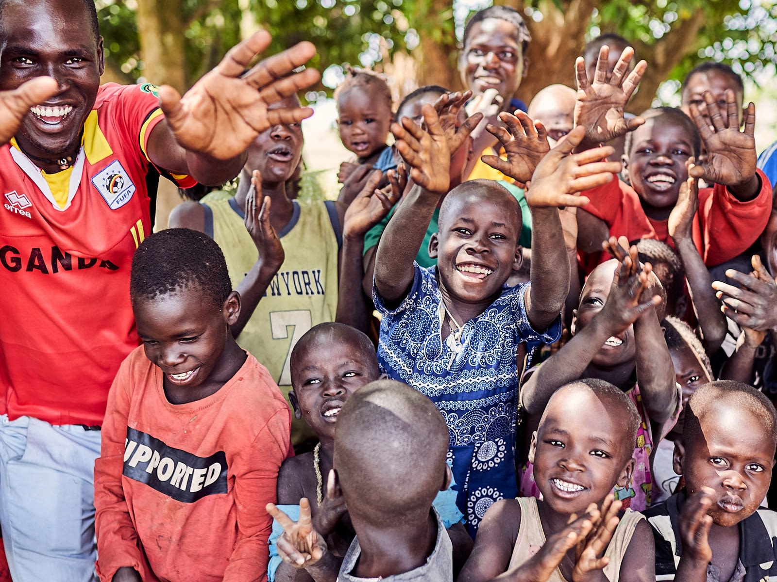 A group of smiling and laughing kids crowd together for a photo.