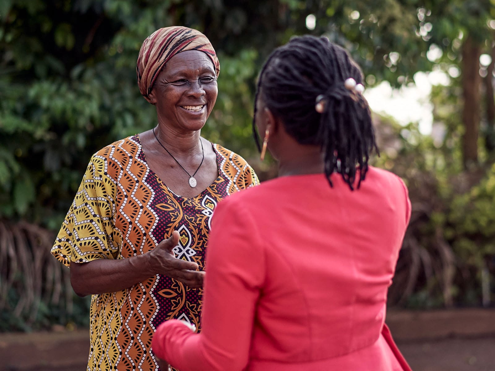 Two women greeting. One in modern business attire, the other in traditional garb