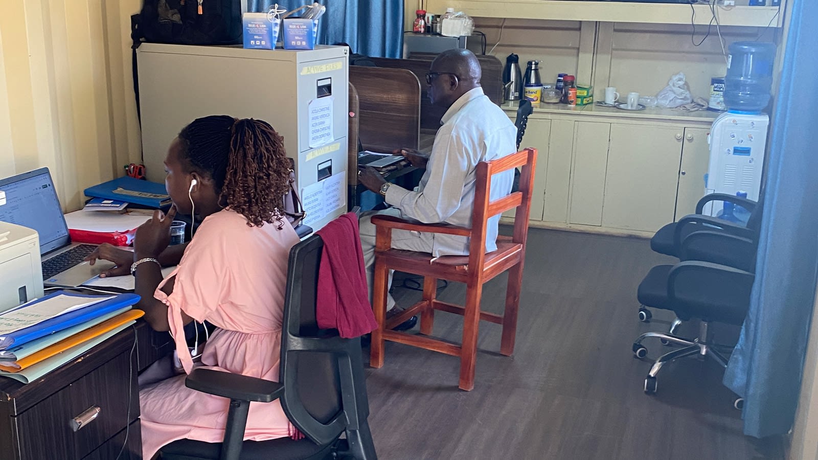 A man and woman work on computers in a small office.