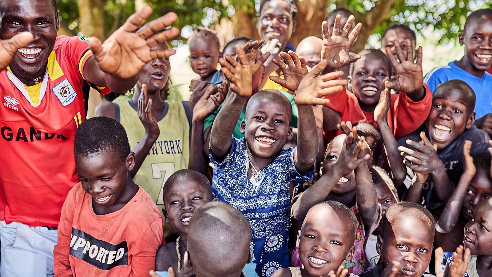 A group of smiling and laughing kids crowd together for a photo.