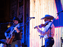 Cowboy musicians perform with acoustic guitar and fiddle