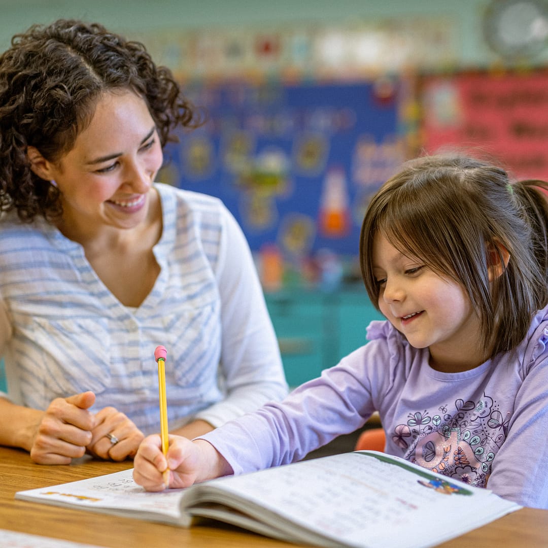 Female teachers works with a young student on a worksheet