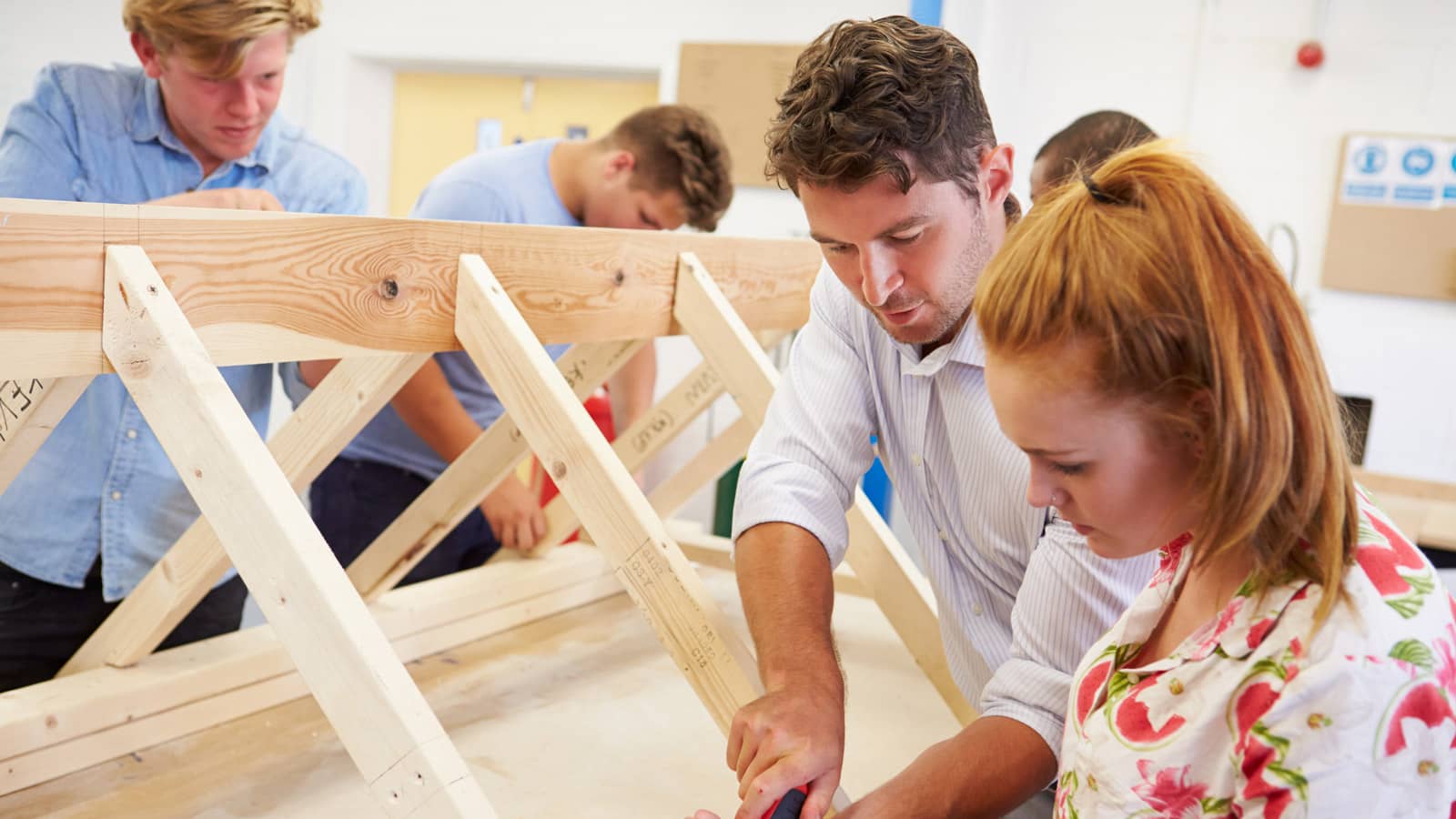 Woodworking teacher demonstrating craft to high school students