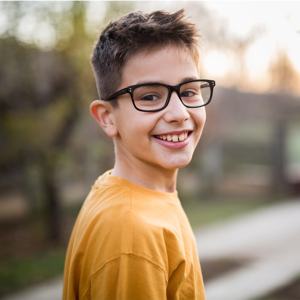 Smiling boy wearing glasses outdoors