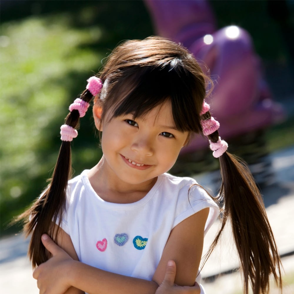 Smiling girl with pigtails in sunny park