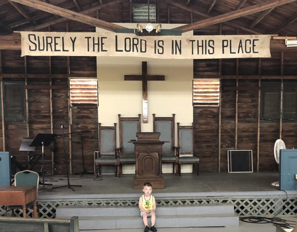 Child sits in front of church altar and banner.