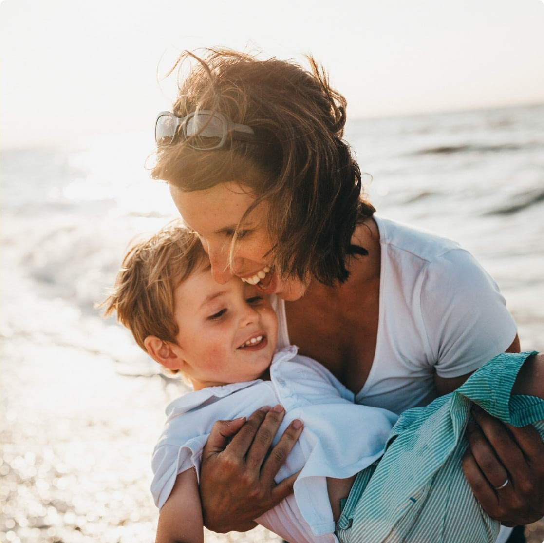 Mother holding child and smiling at beach