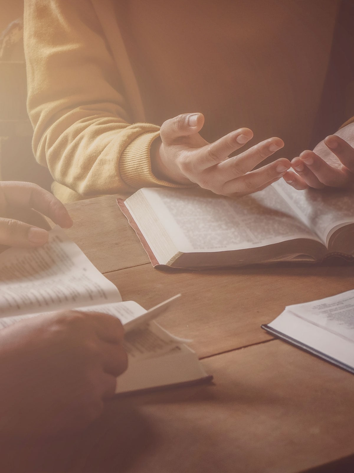 People discussing and reading books at a table.
