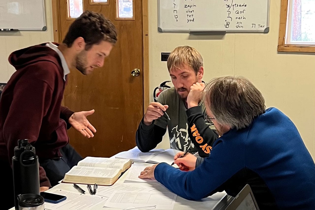 Three men studying with open book at table