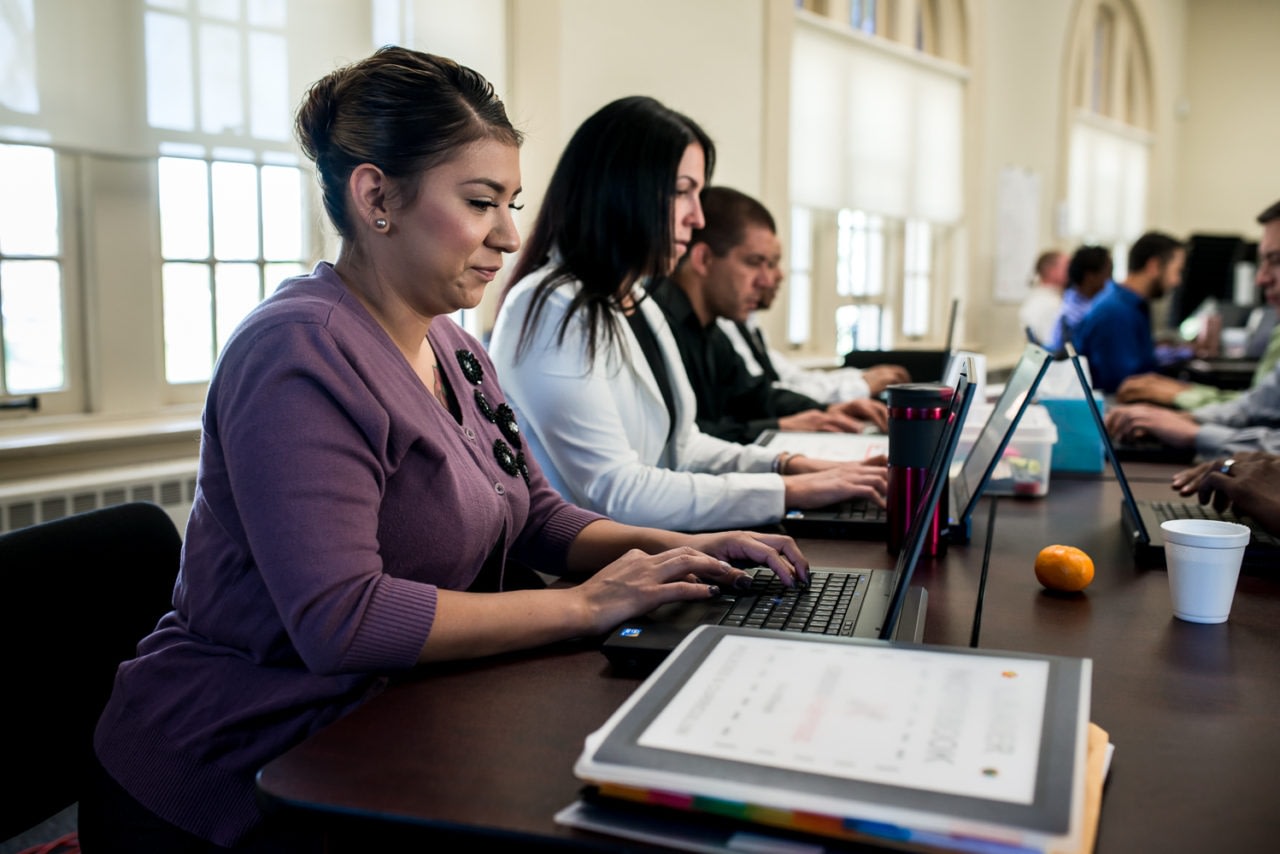 Adults working on laptops in classroom setting