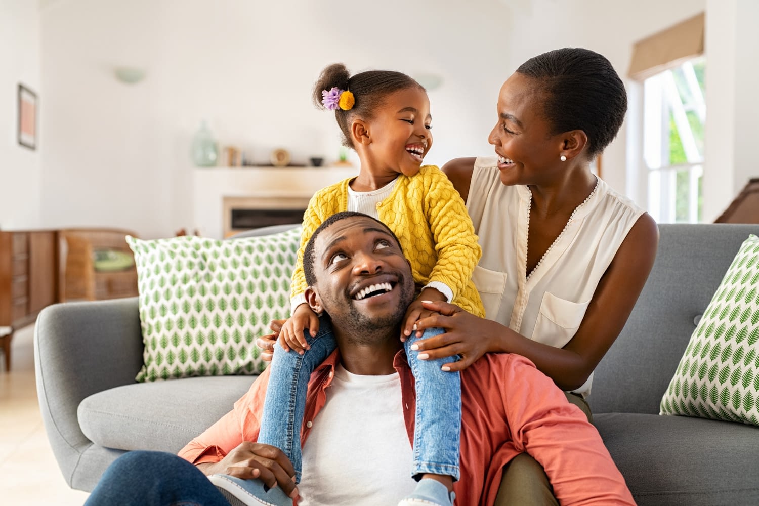 A father, mother, and daughter laugh together.