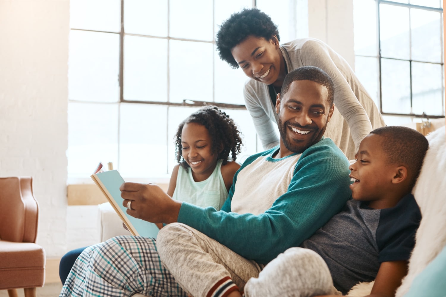 Family reads a book together and laughs.