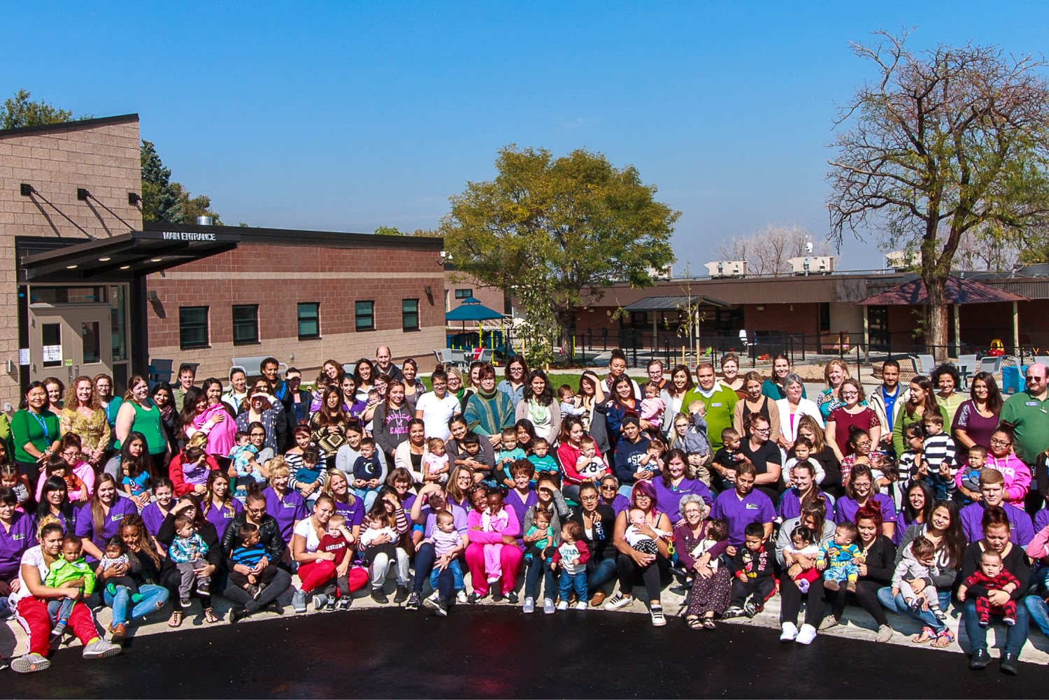 Large group photo outside a building on sunny day.