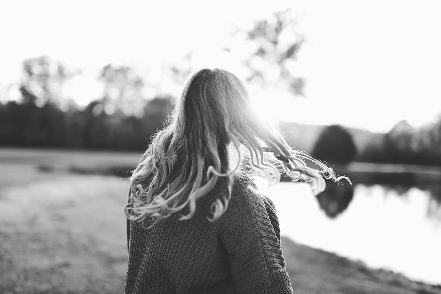 Woman by lake at sunset with flowing hair