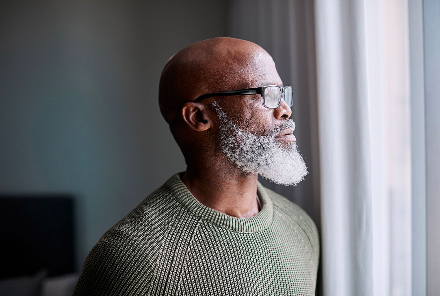 Middle-aged man looking out a window thoughtfully