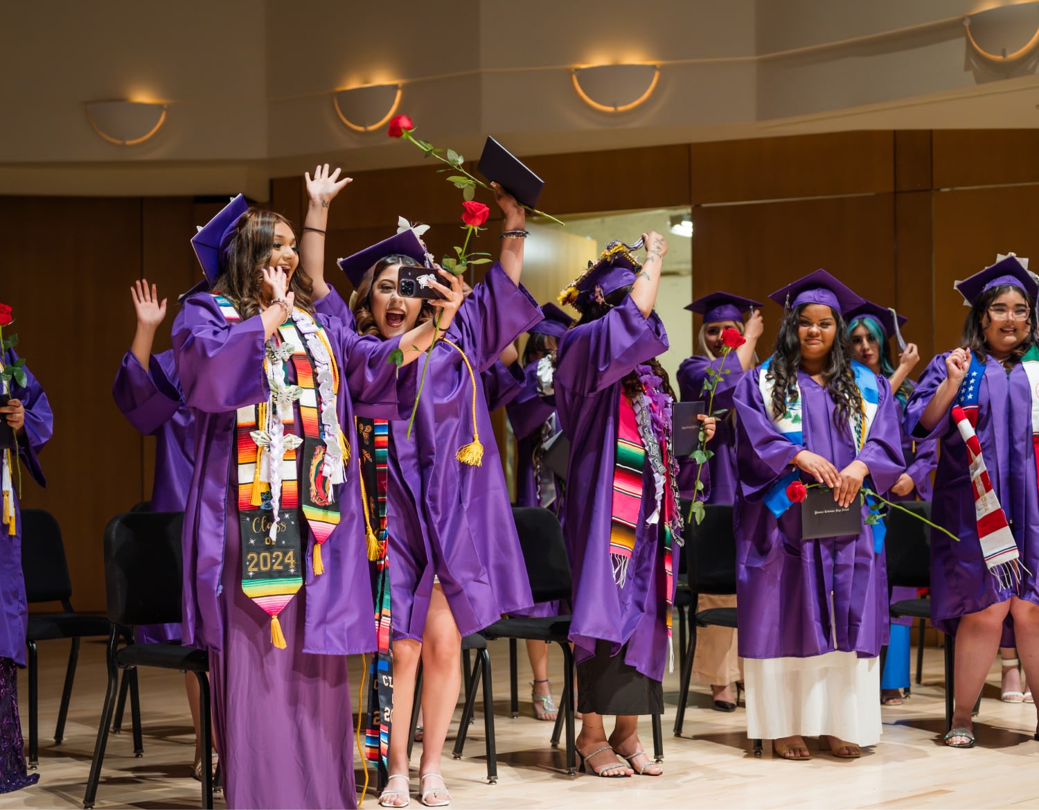 Students celebrate graduation in purple caps and gowns.