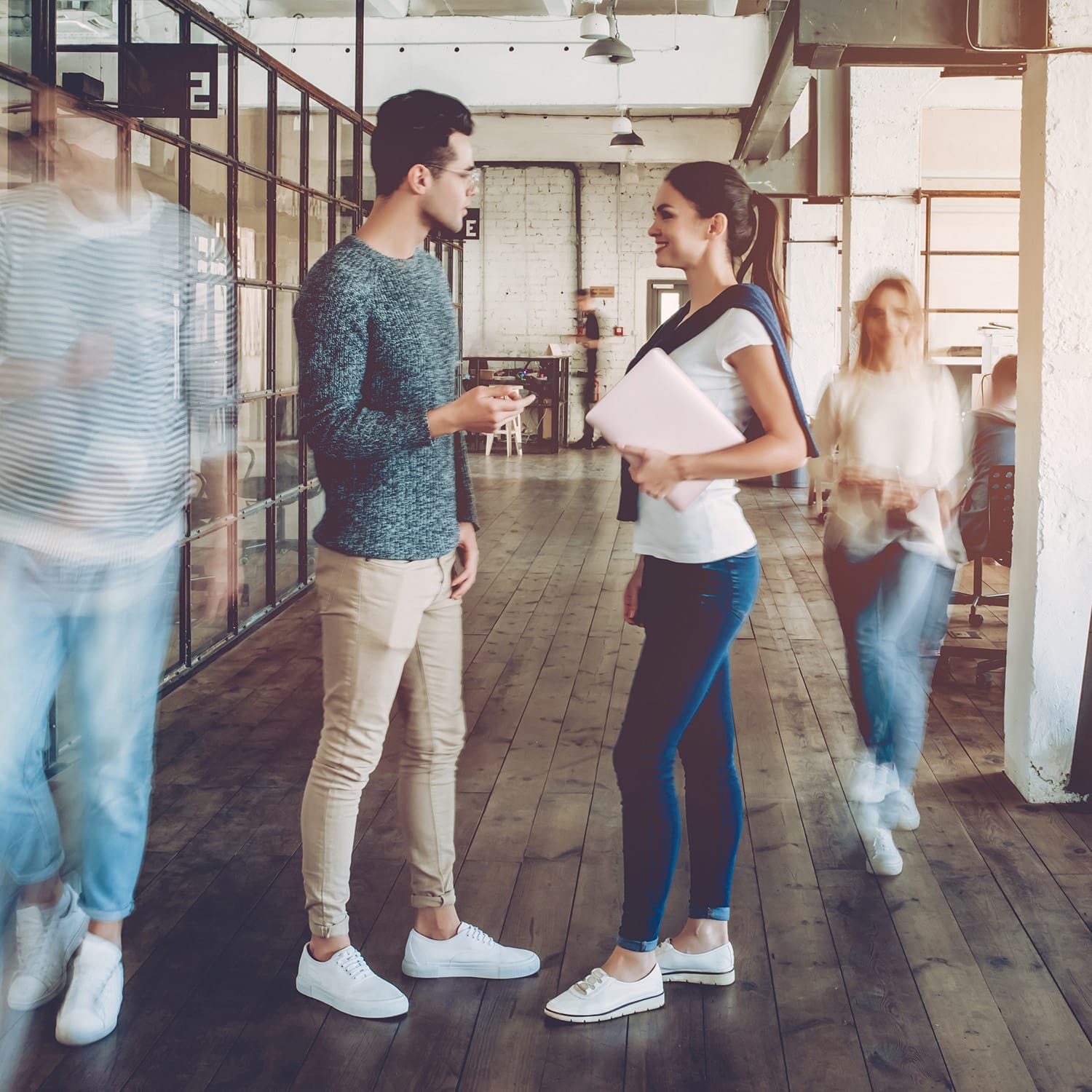 People talking in modern office hallway.