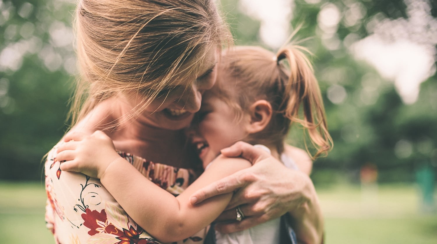 Mother hugging child outdoors happily
