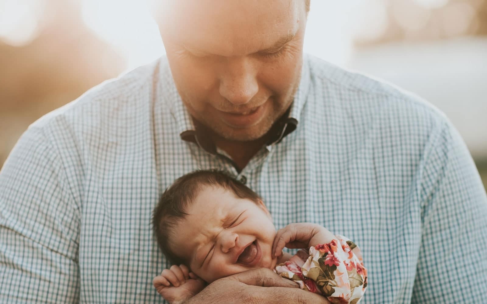 Man holding smiling newborn baby outdoors