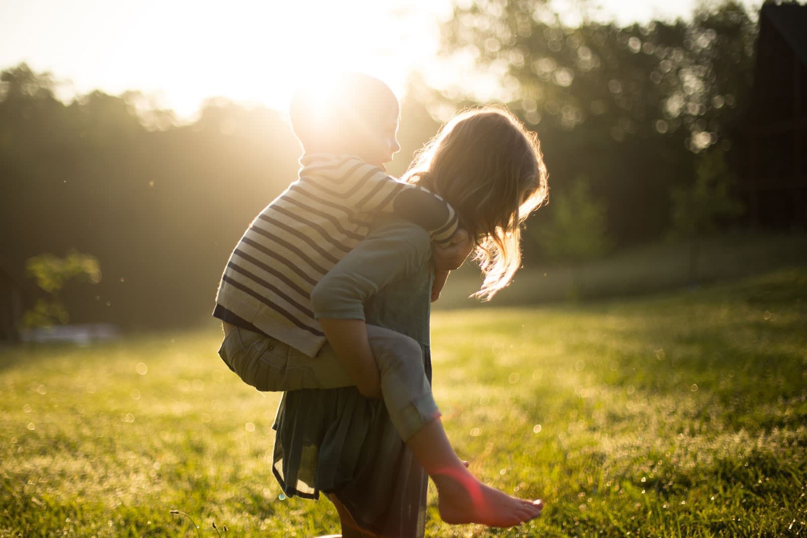 Child giving piggyback ride in sunny field