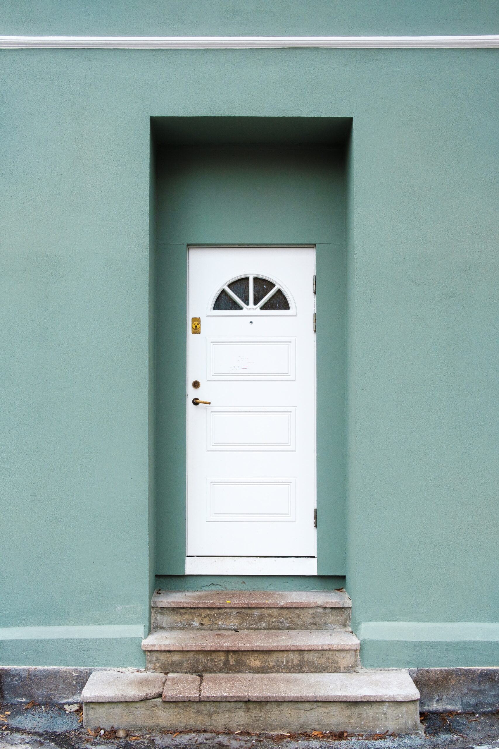 White door on green wall with concrete steps