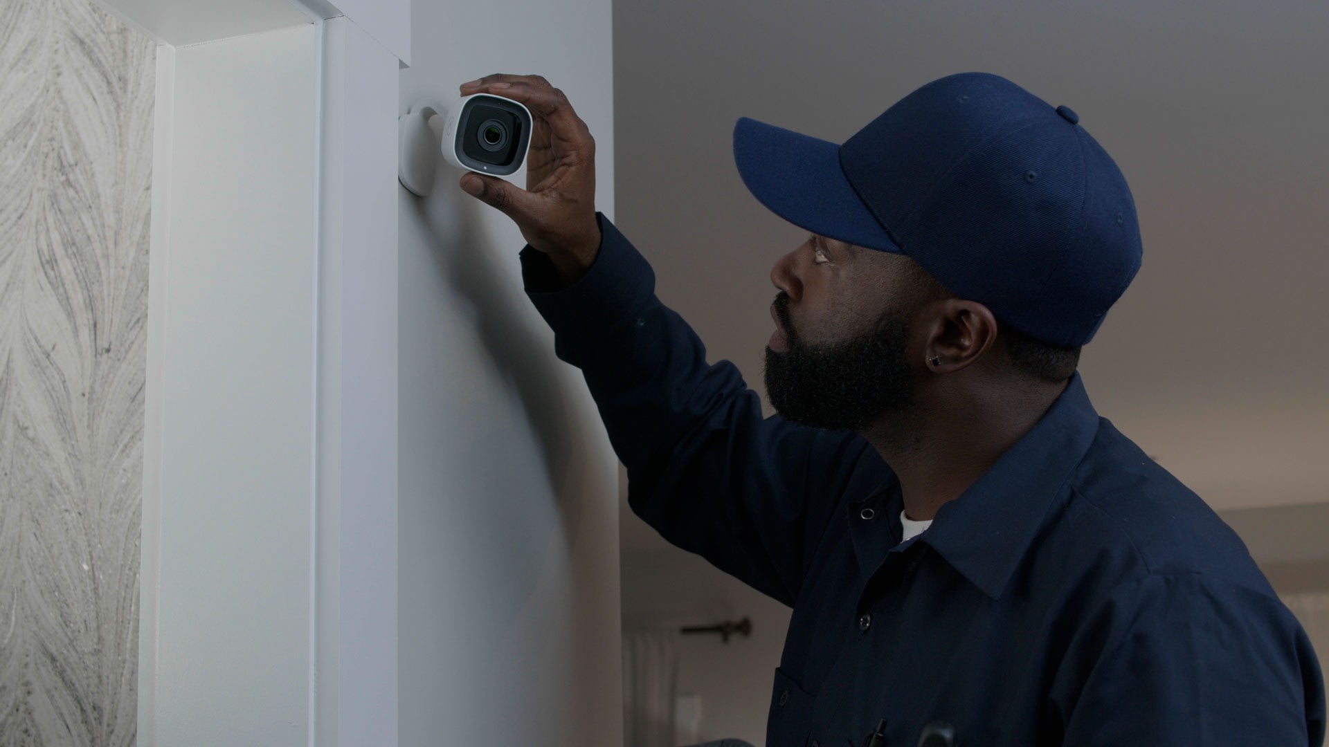 Technician installing indoor home security camera on wall