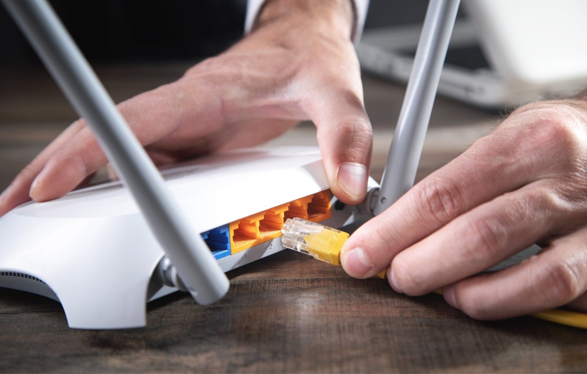 Person connecting Ethernet cable to WiFi router