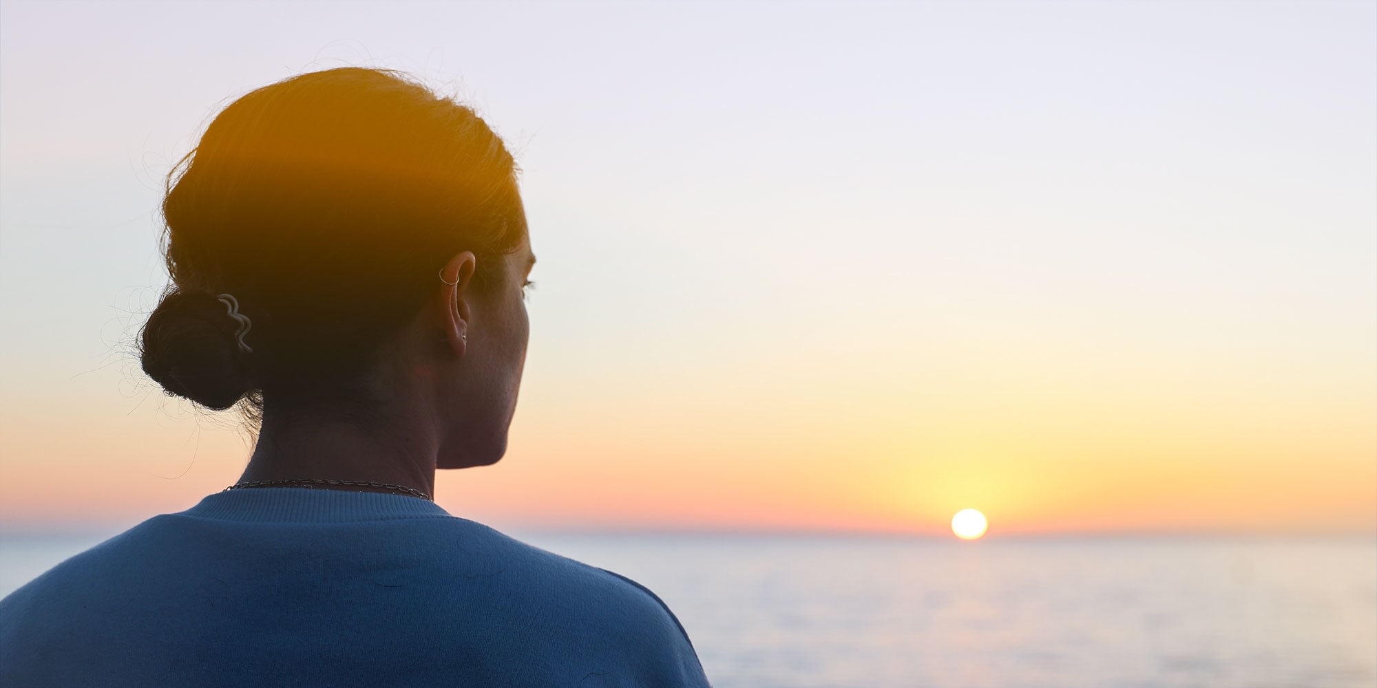 Young woman looking at a sunrise on the ocean