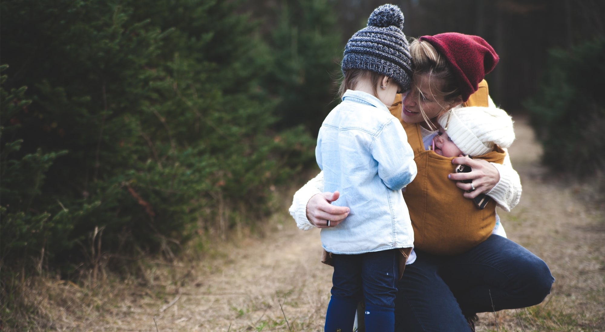 Mother hugging children outdoors in nature