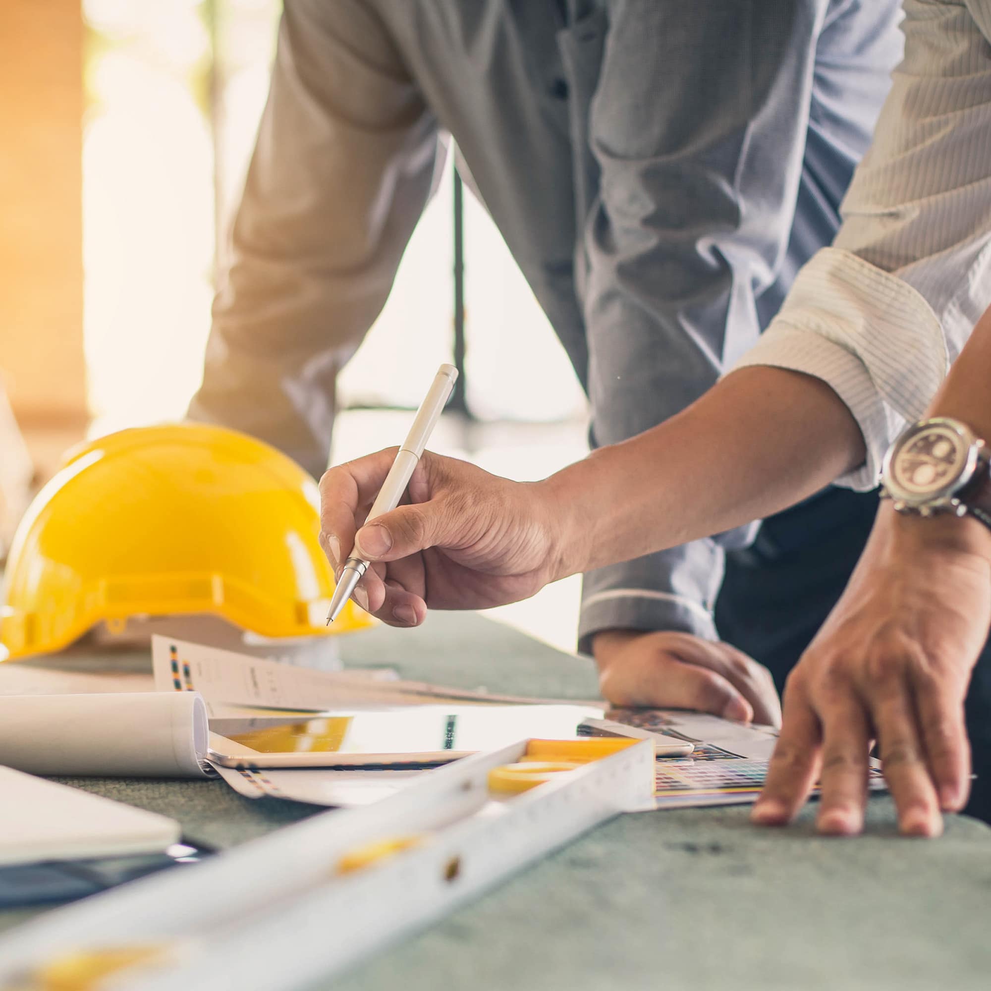 Architects planning with yellow hard hat on table.