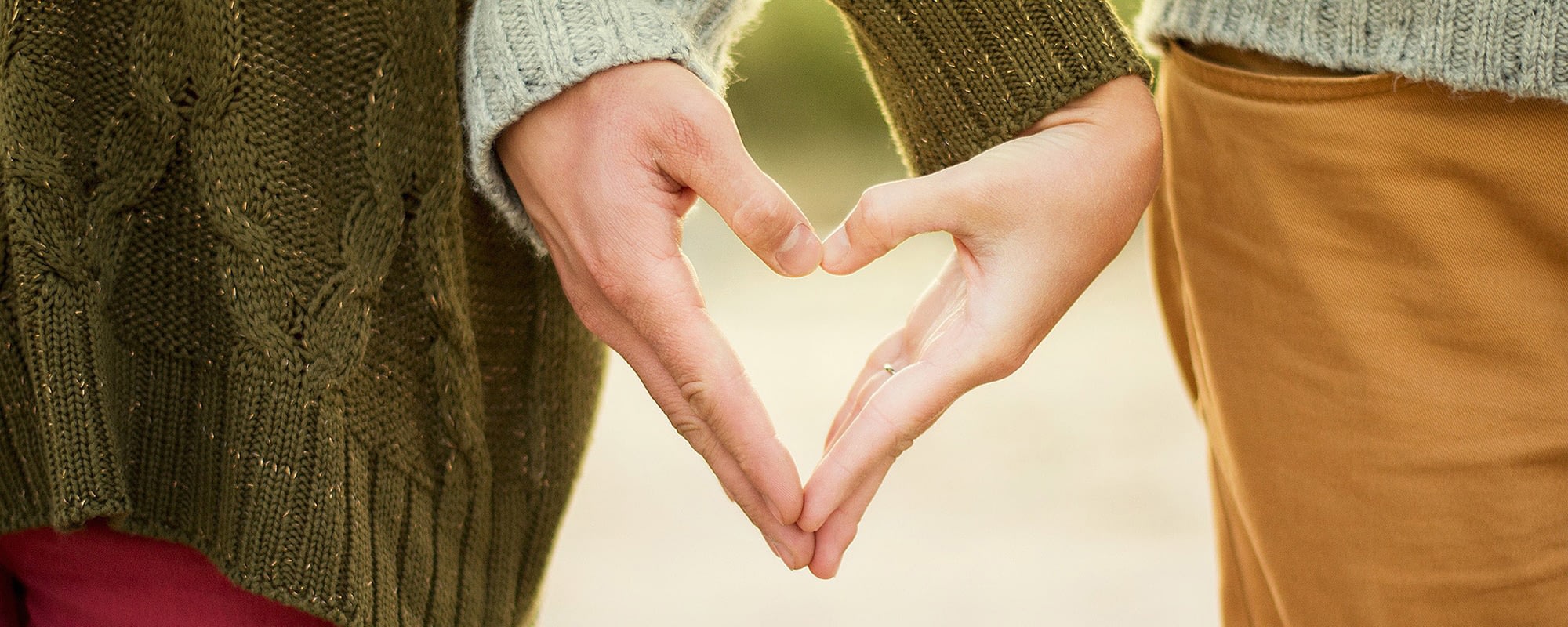 Two people forming a heart with hands