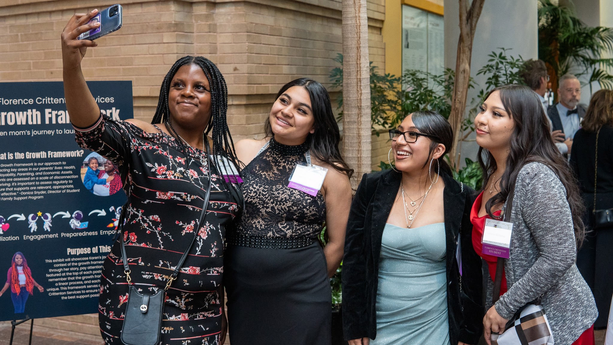 Four women taking a group selfie at an event.