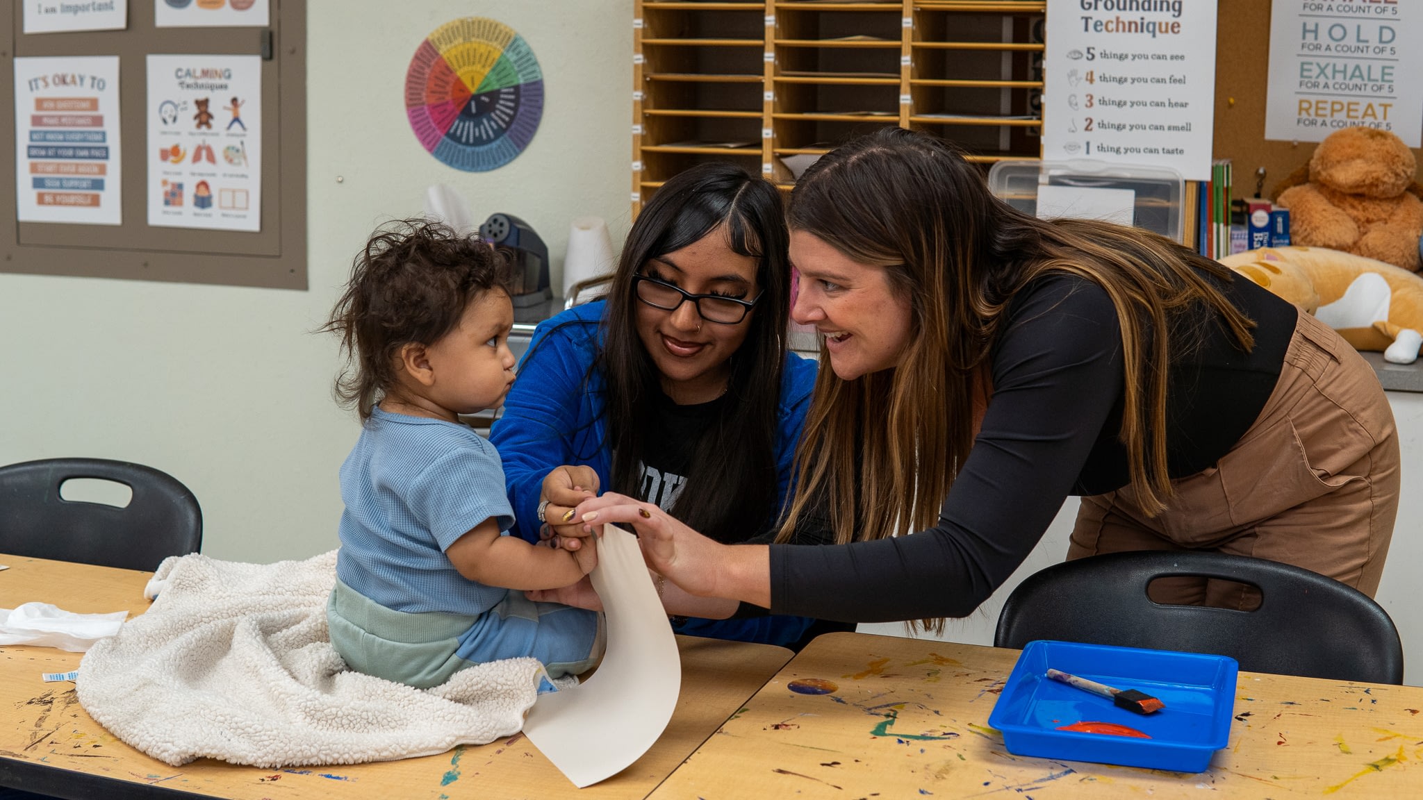 Teacher helping a toddler with art project.