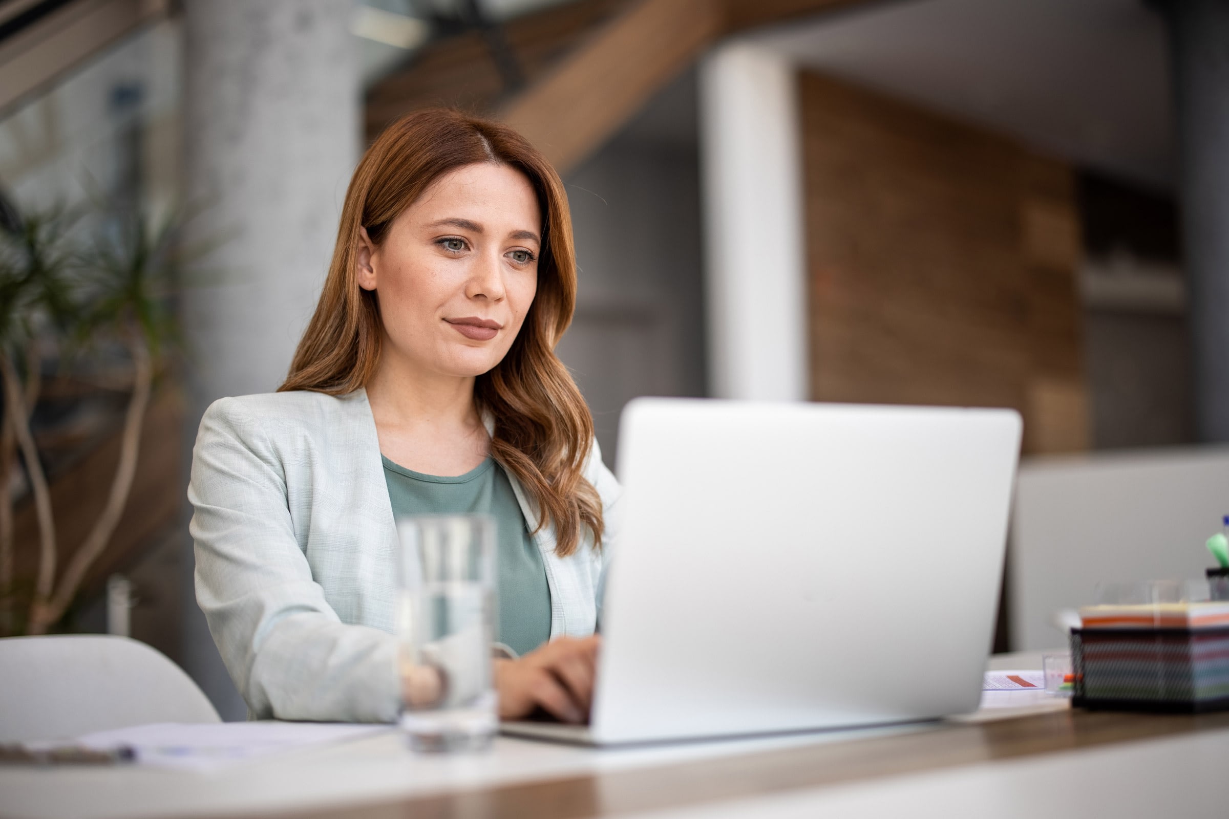 Woman working on laptop in office setting.