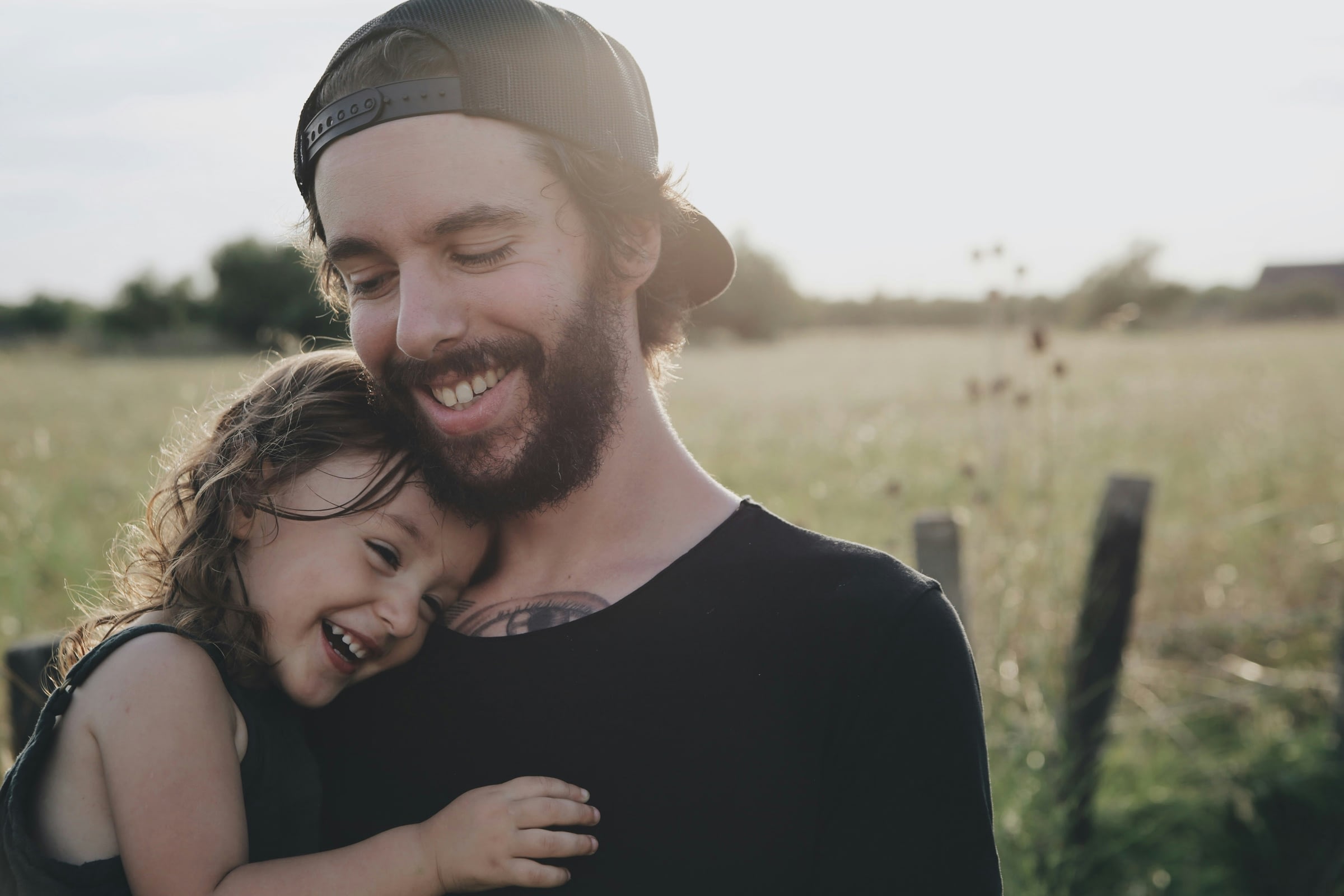 Smiling man hugging happy child outdoors