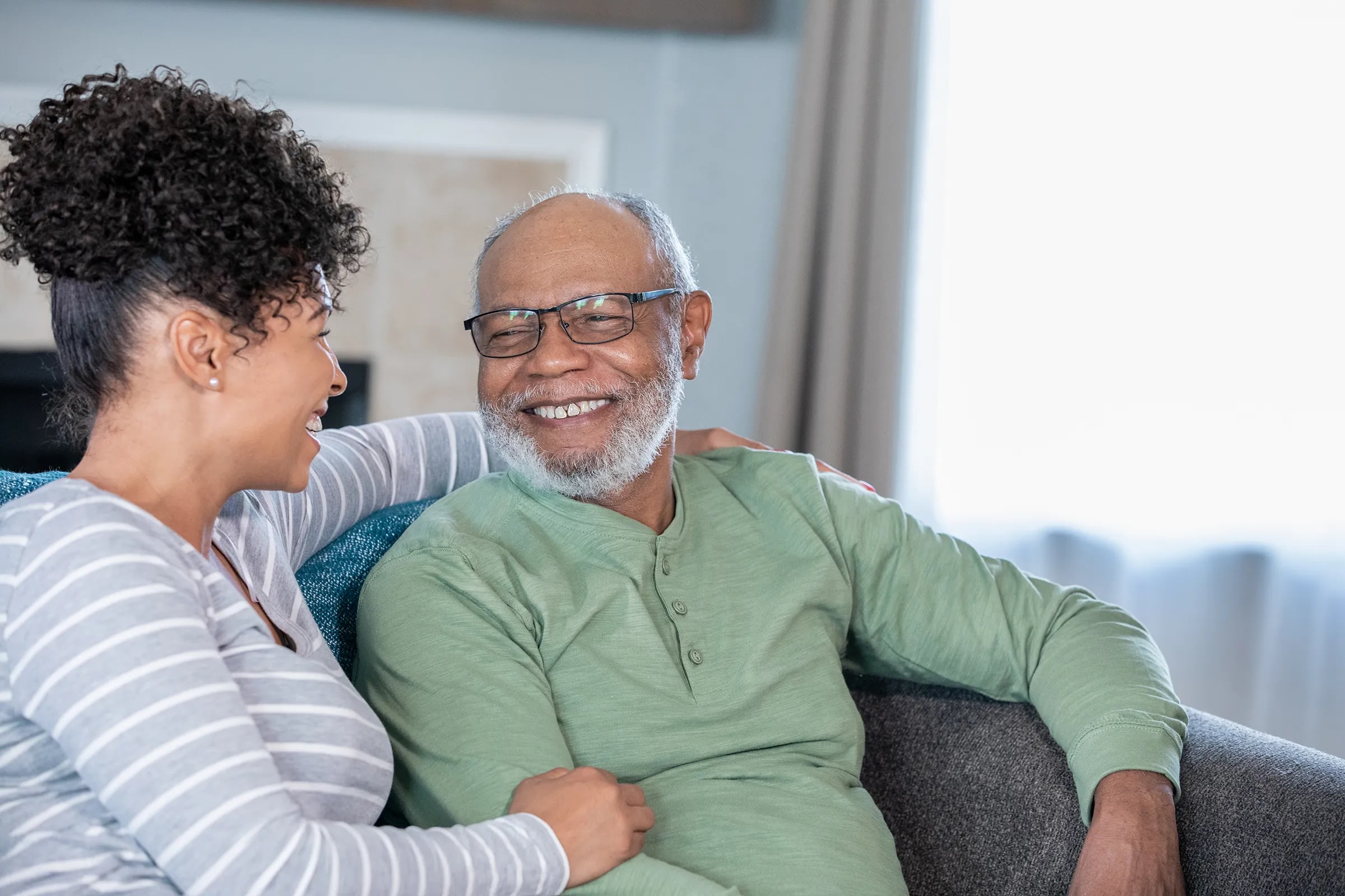 Two people smiling together on living room couch