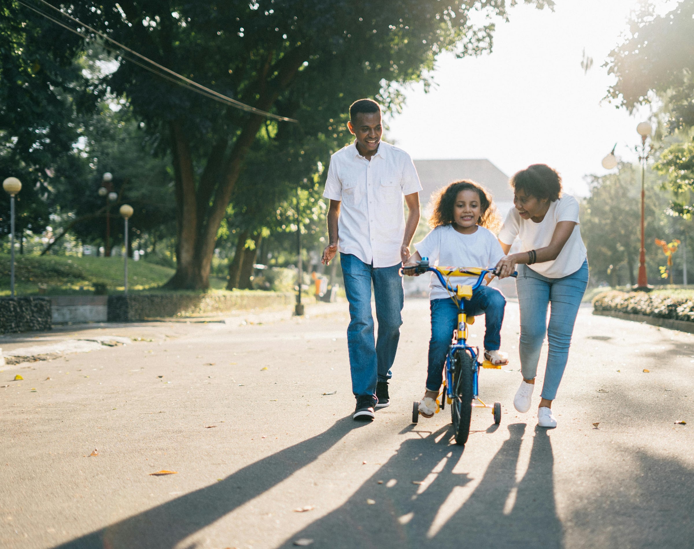 Parents teaching child to ride bike outdoors