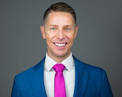 Smiling man in blue suit and pink tie