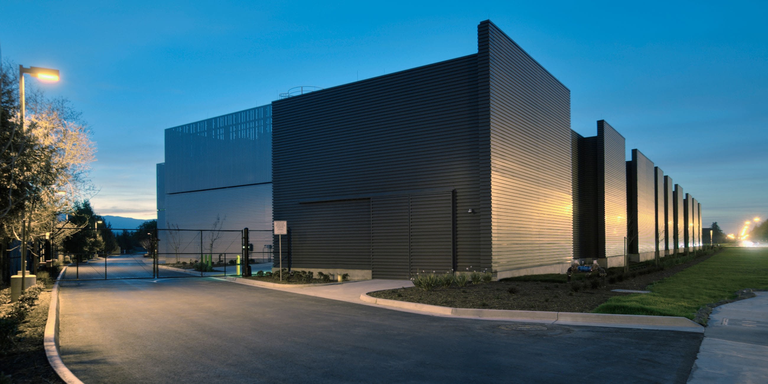 Modern industrial building at dusk with streetlights.
