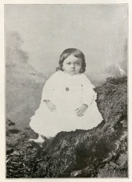 Vintage photo of a baby sitting outdoors.