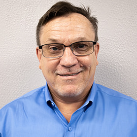 Headshot of Shawn Brewer - man with glasses in a blue collard shirt