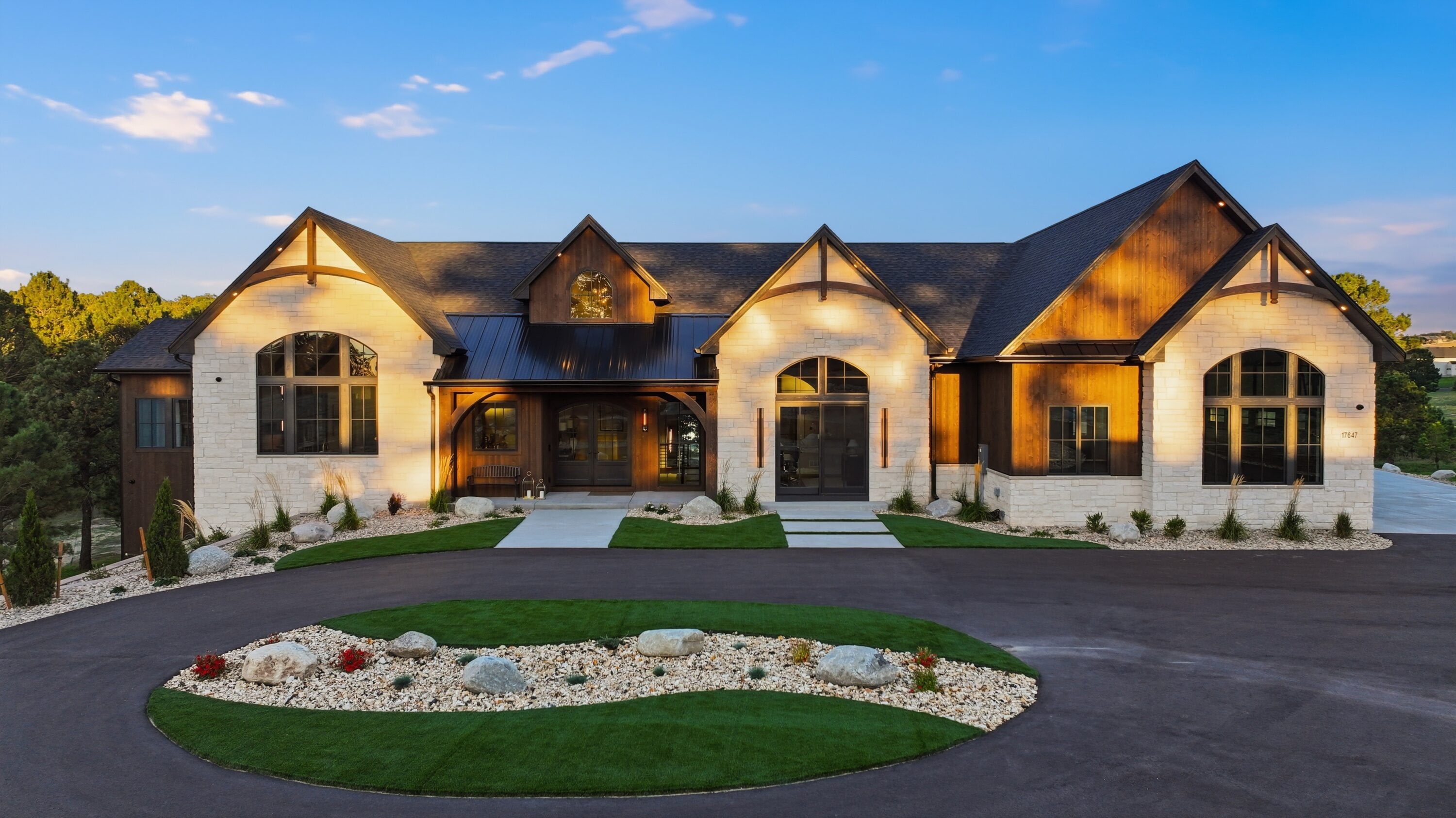 Illuminated modern farmhouse with stone facade at dusk